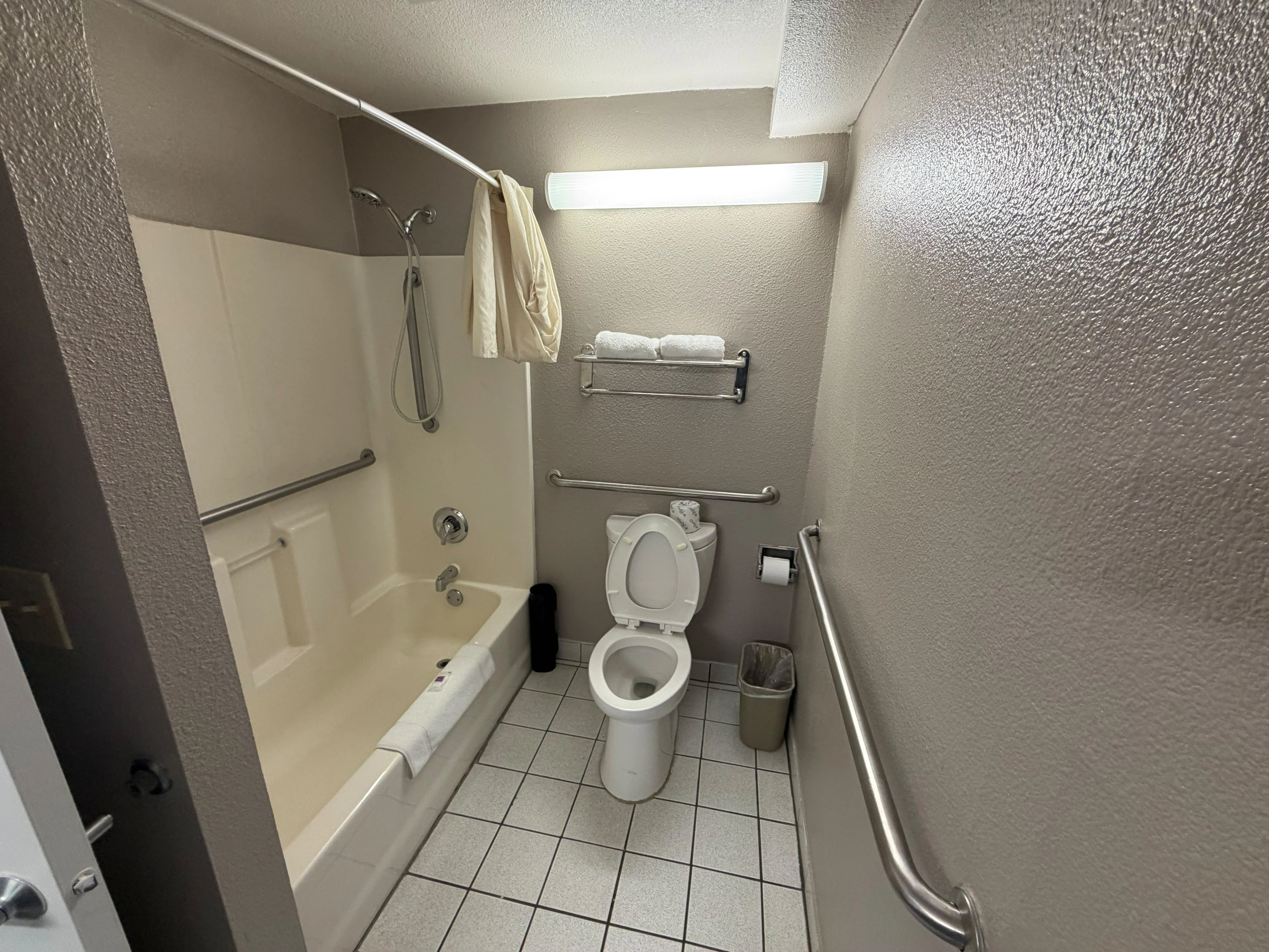 Mobility-accessible bathroom with grab bars and bathtub
