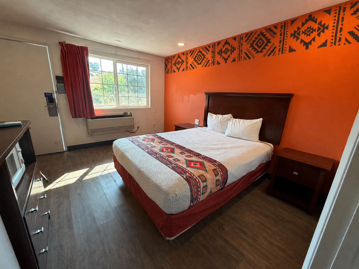 Queen room with a hand-painted geometric border on the orange accent wall