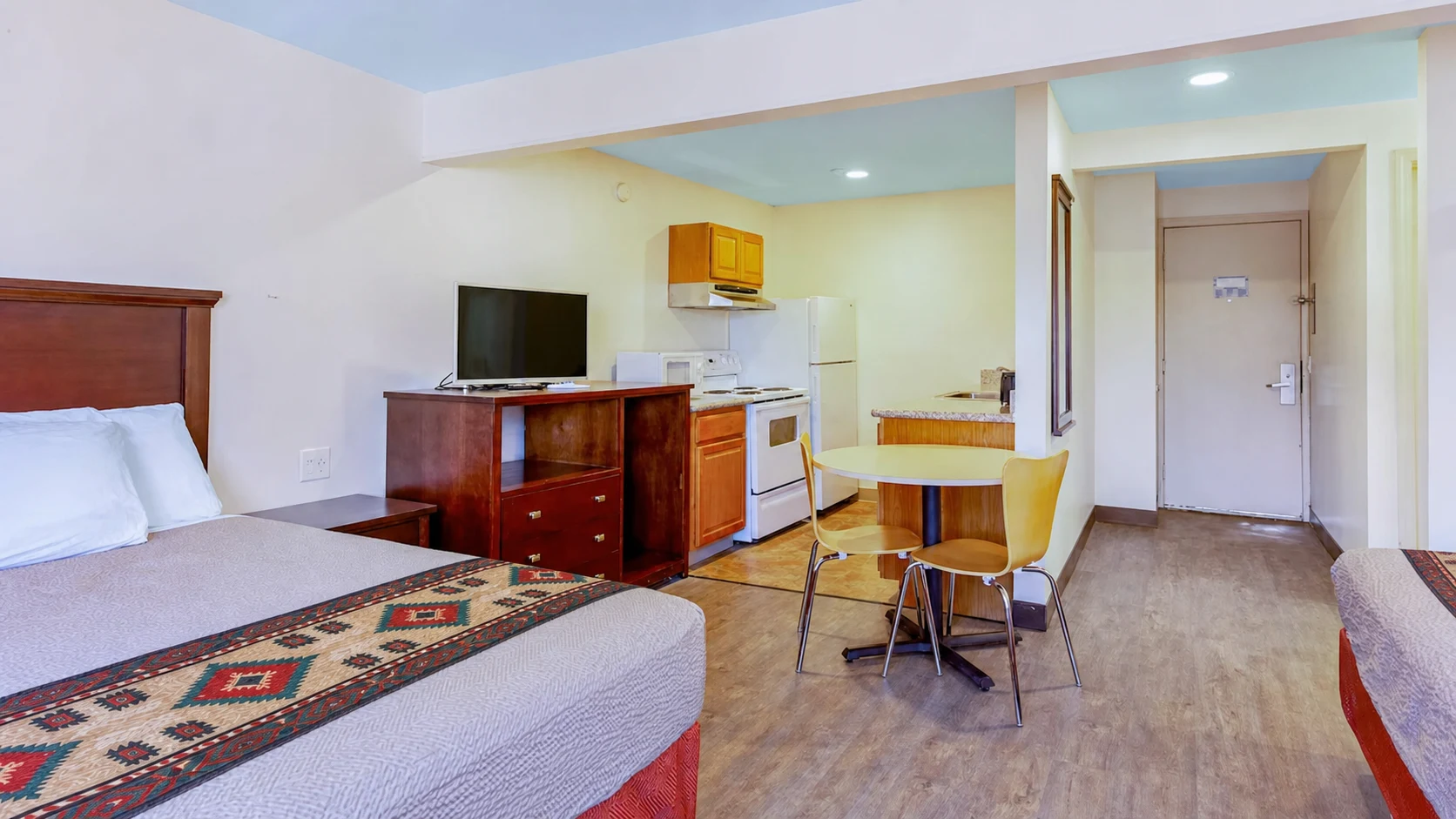 Kitchenette, dining table, and sleeping area in the three-queen room with Southwestern-style bed runners