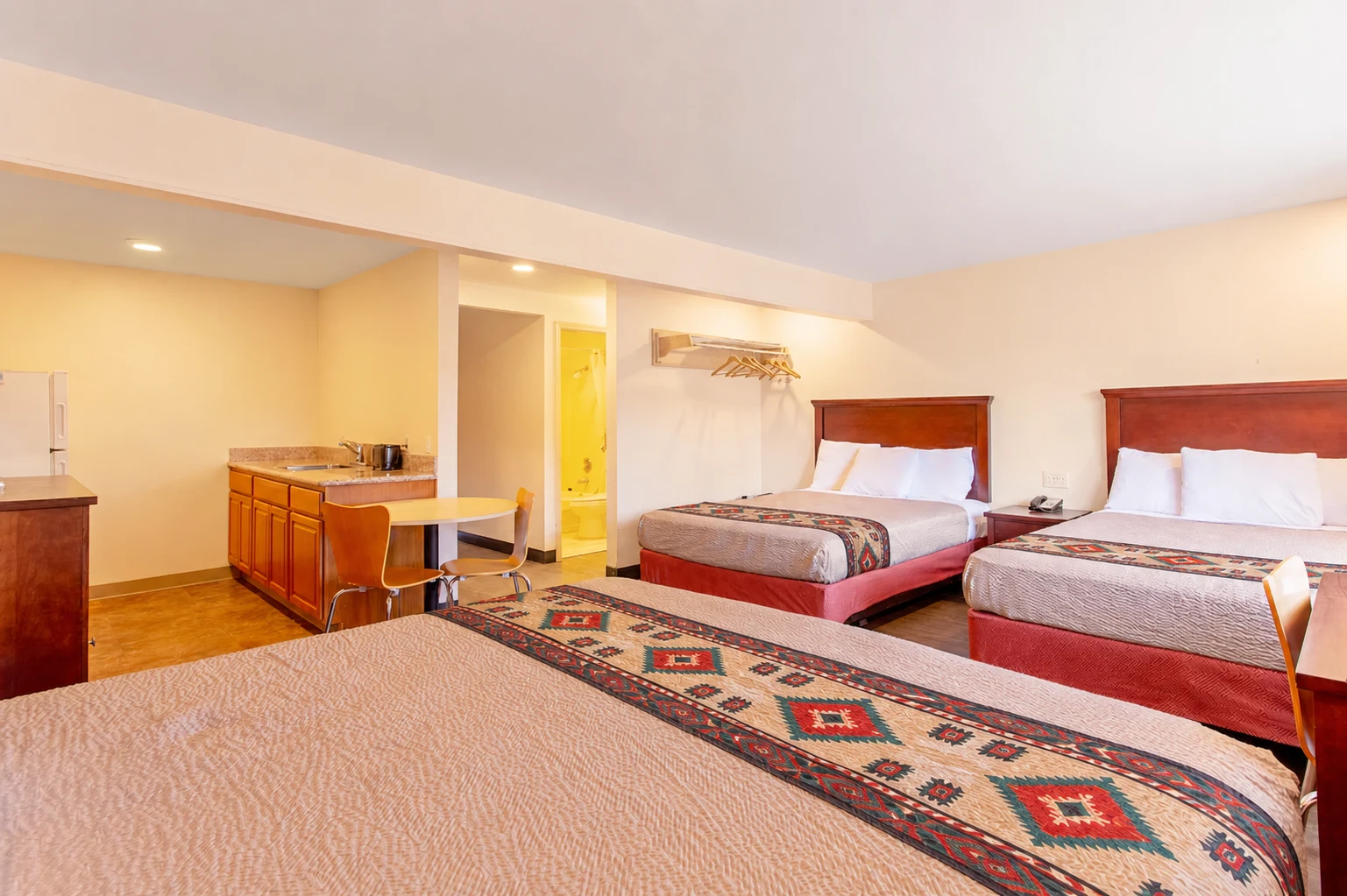 Large guest room with three queen beds, a kitchenette, and Southwestern-style bed runners