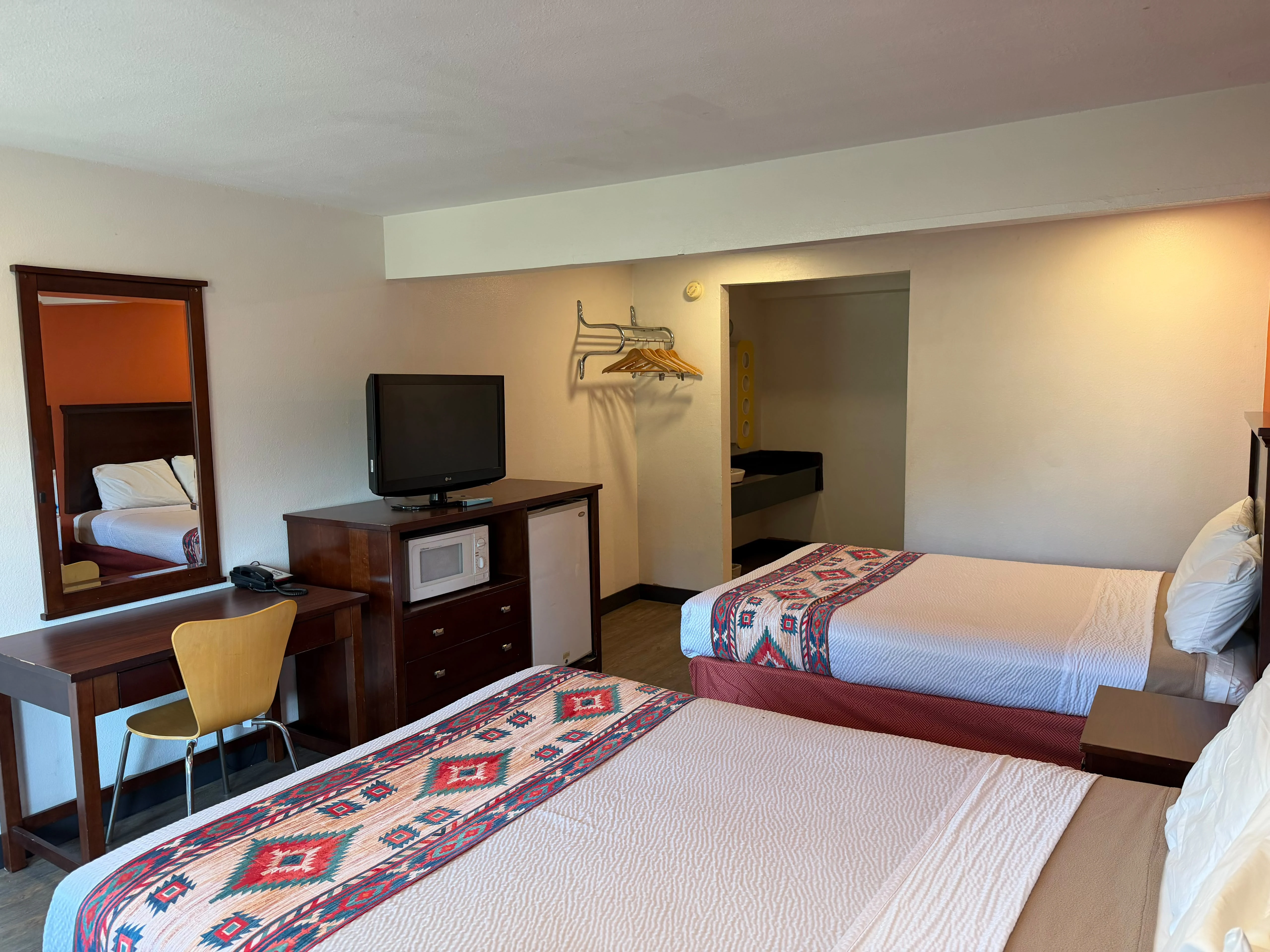Two-queen guest room with microwave, refrigerator, desk, and television